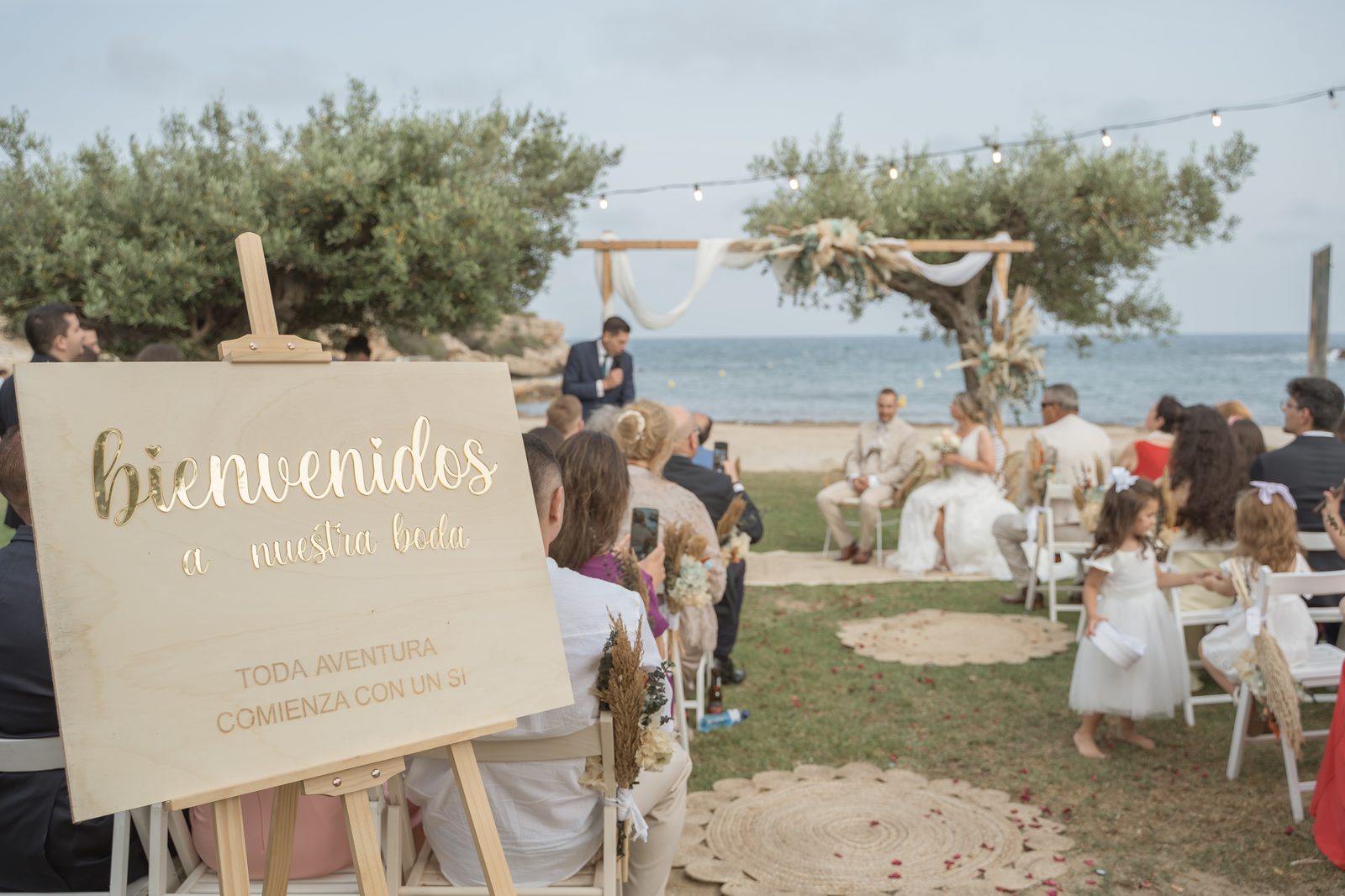 Ceremonia de boda en la playa al atardecer, con arco de flores secas junto al mar