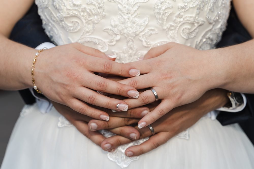 Manos entrelazadas de los novios mostrando las alianzas