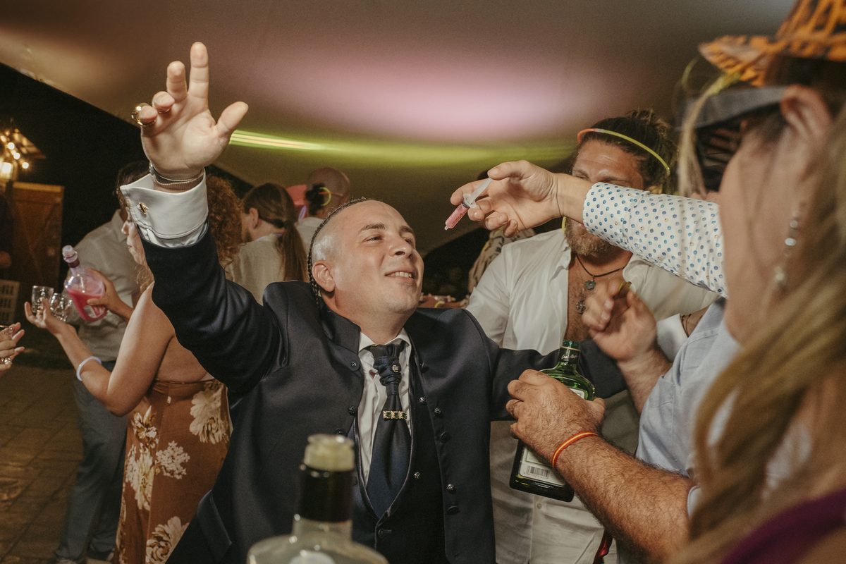 Invitado bailando y brindando en plena fiesta de noche