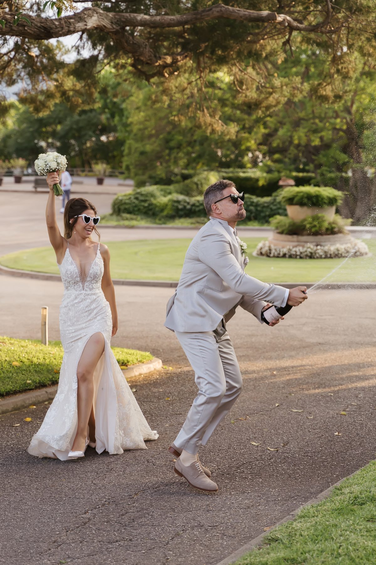 Novios celebrando con gafas de corazón y una botella descorchada